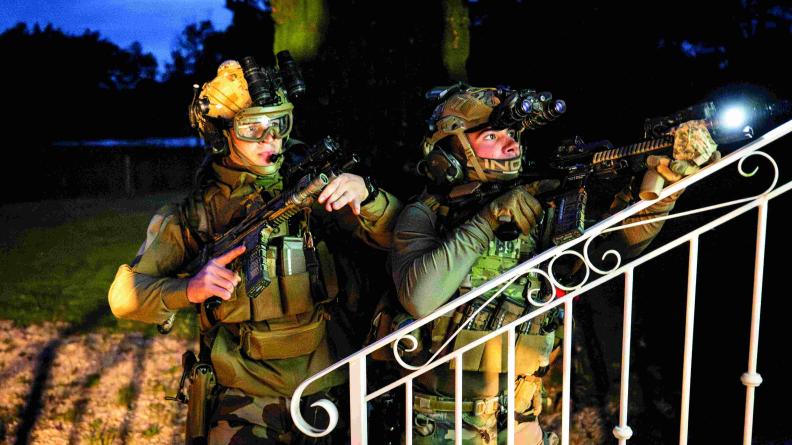 Deux légionnaires équipés de jumelles de vision nocturne progressent de nuit, armes prêtes